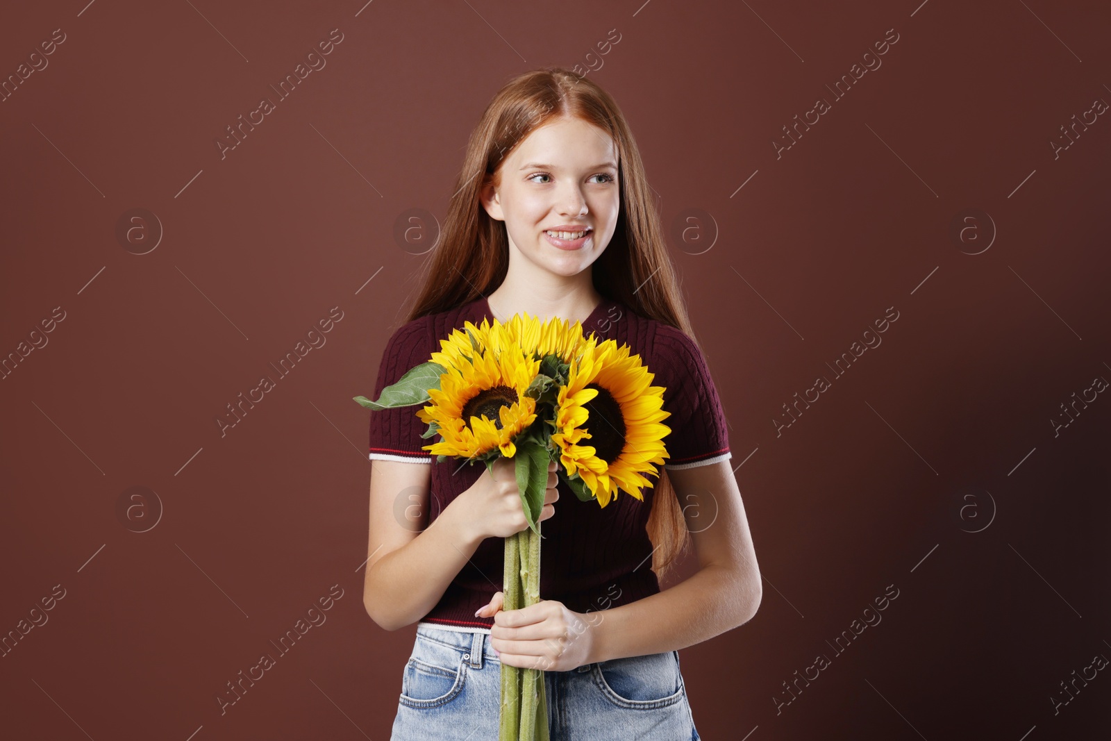 Photo of Teenage girl with bouquet of beautiful sunflowers on brown background