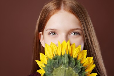 Photo of Teenage girl with beautiful sunflower on brown background