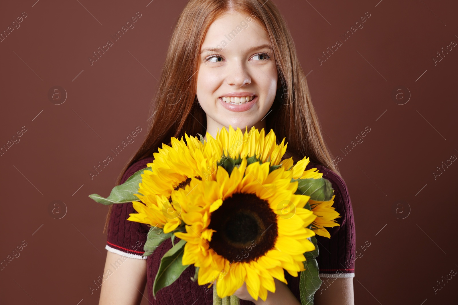 Photo of Teenage girl with bouquet of beautiful sunflowers on brown background