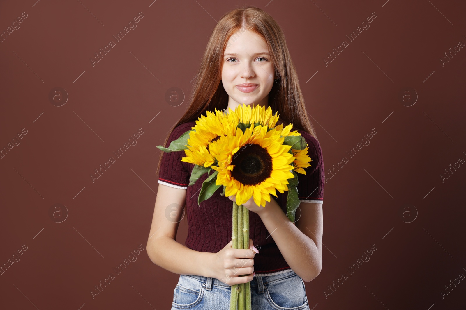Photo of Teenage girl with bouquet of beautiful sunflowers on brown background