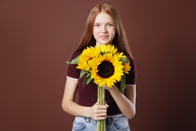 Photo of Teenage girl with bouquet of beautiful sunflowers on brown background