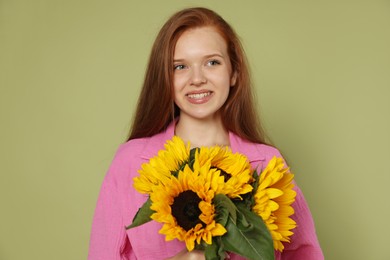 Photo of Teenage girl with bouquet of beautiful sunflowers on green background