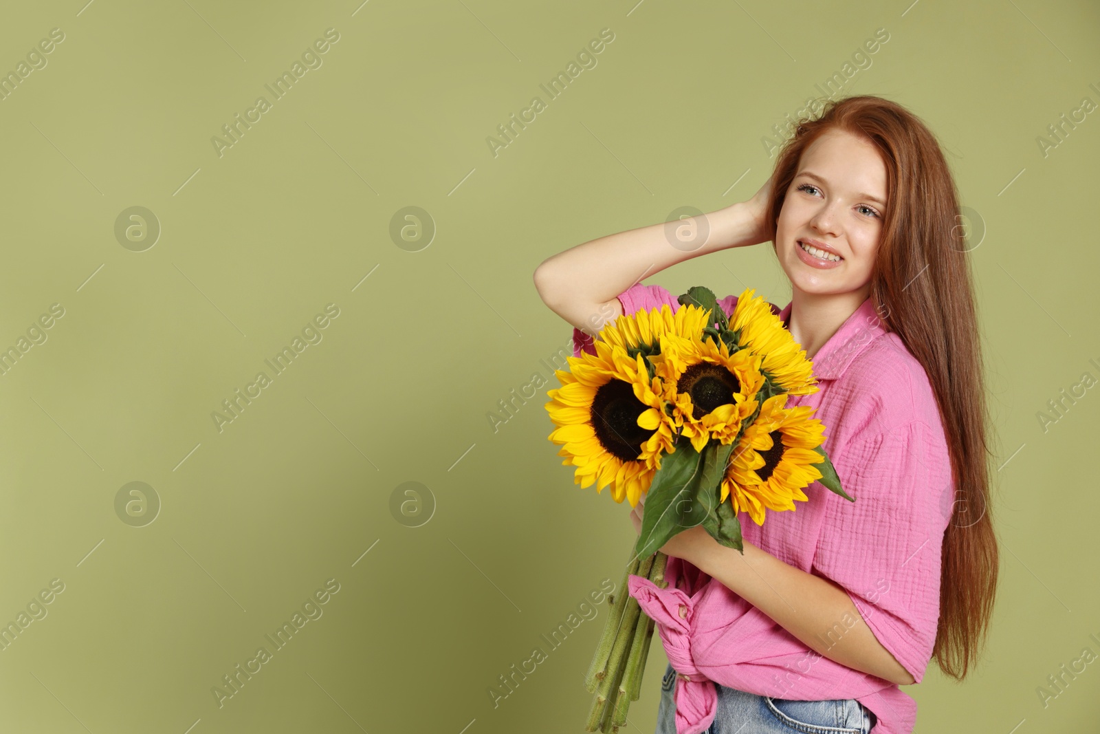 Photo of Teenage girl with bouquet of beautiful sunflowers on green background, space for text