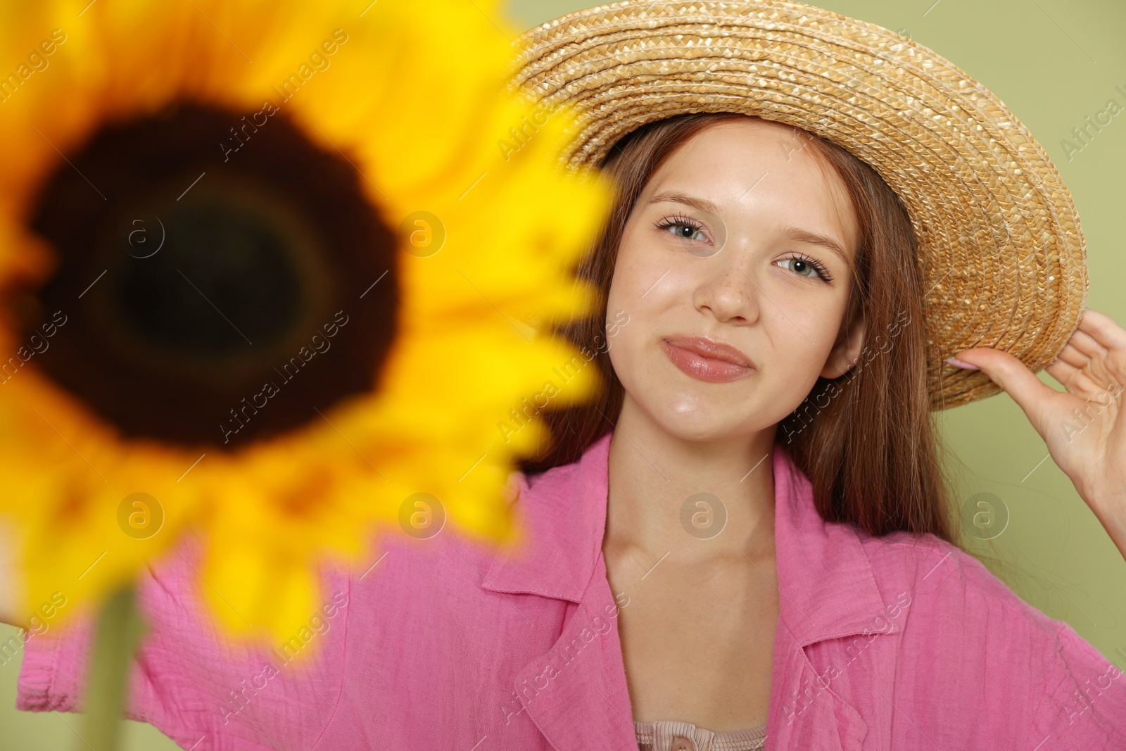 Photo of Teenage girl with beautiful sunflower on green background, selective focus