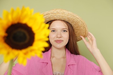 Photo of Teenage girl with beautiful sunflower on green background, selective focus