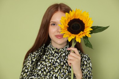Photo of Teenage girl with beautiful sunflower on green background