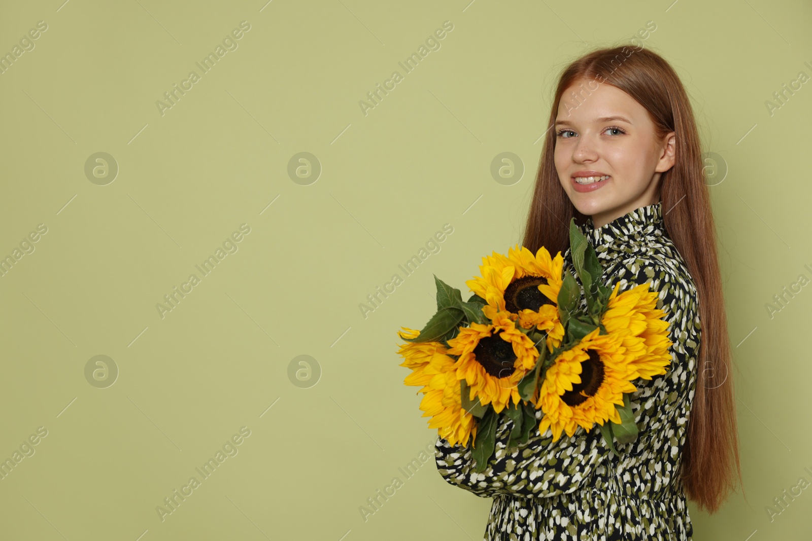 Photo of Teenage girl with bouquet of beautiful sunflowers on green background, space for text
