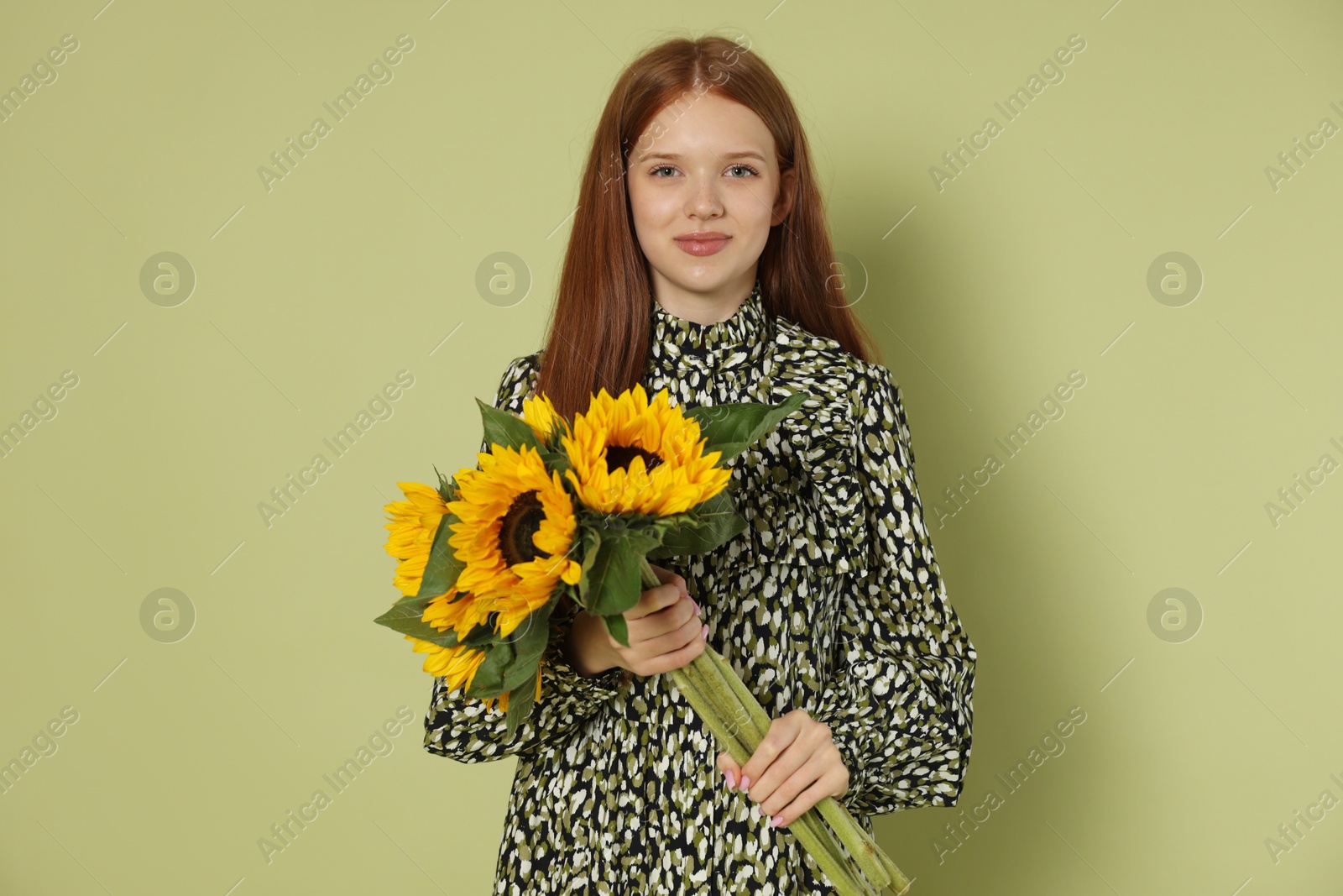 Photo of Teenage girl with bouquet of beautiful sunflowers on green background