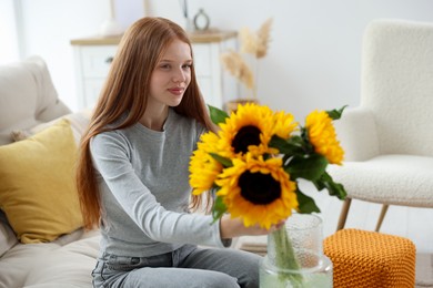 Photo of Teenage girl with beautiful sunflowers at home