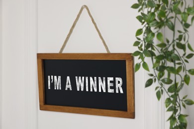 Image of Chalkboard with phrase I'm A Winner hanging on white door