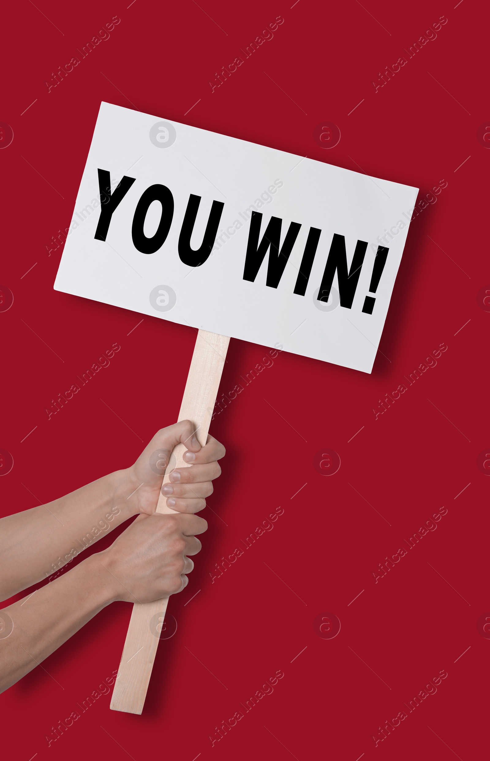 Image of Man holding sign with phrase You Win against dark red background, closeup