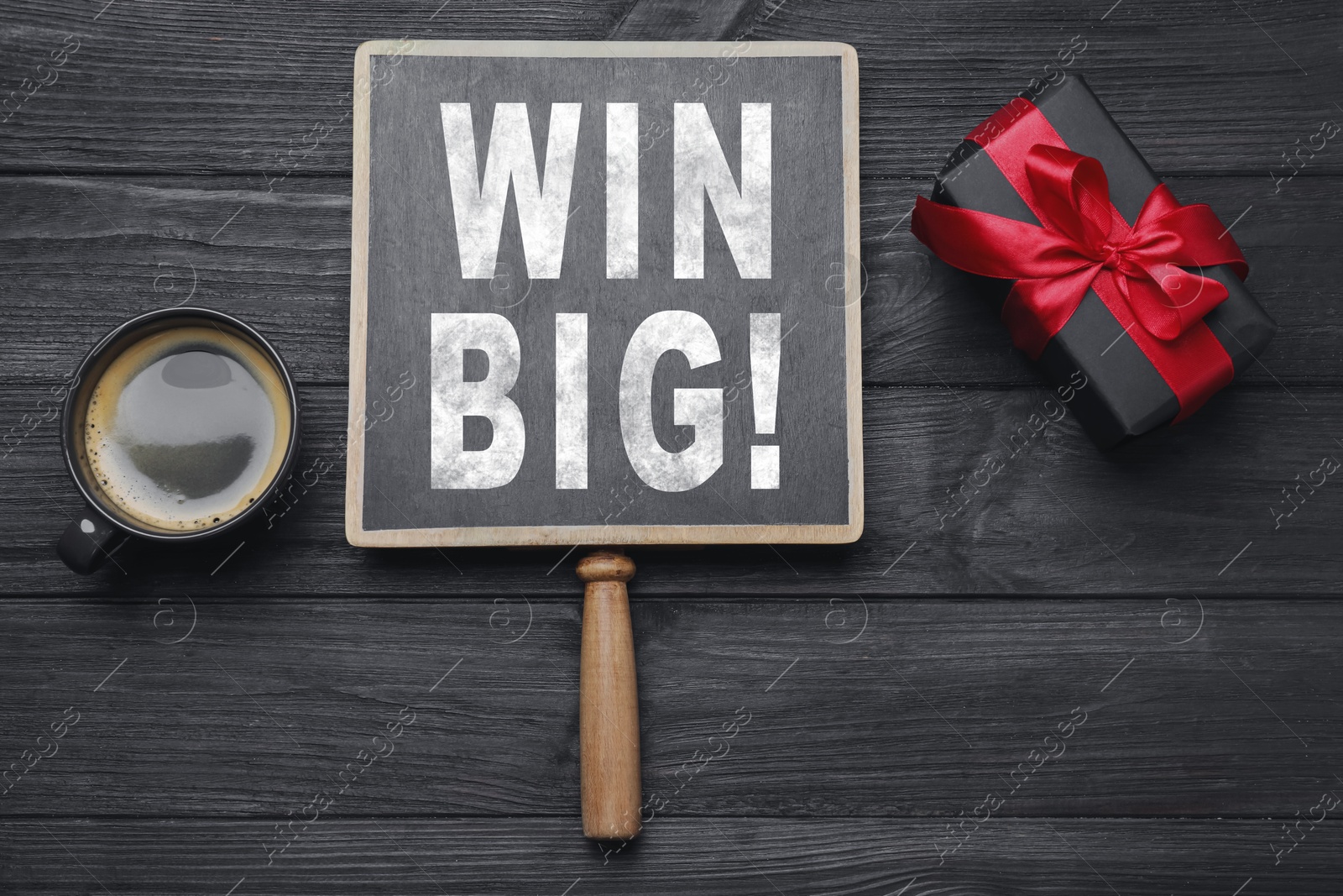 Image of Chalkboard with phrase Win Big, gift box and coffee on black wooden table, top view