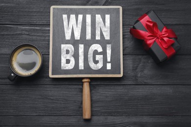 Image of Chalkboard with phrase Win Big, gift box and coffee on black wooden table, top view