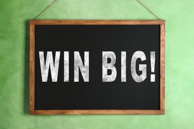 Image of Chalkboard with phrase Win Big hanging on light green wall