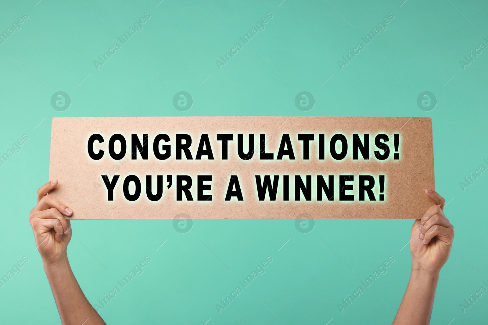 Image of Man holding sign with phrase Congratulations! You're A Winner! against turquoise background, closeup