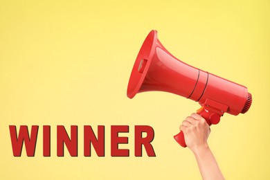 Image of Winner. Woman holding red loudspeaker against yellow background, closeup