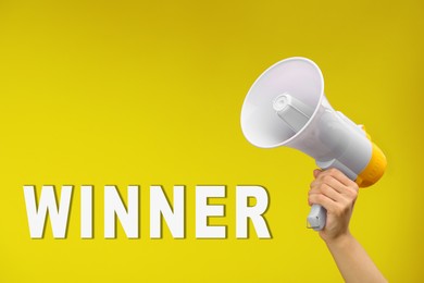 Image of Winner. Woman holding loudspeaker against yellow background, closeup