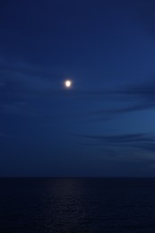 Photo of Moon glowing in night sky over beautiful sea