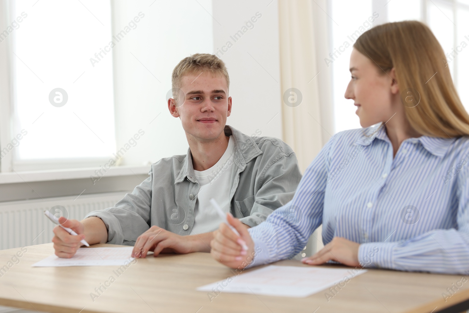 Photo of Students taking exam at wooden table indoors, selective focus