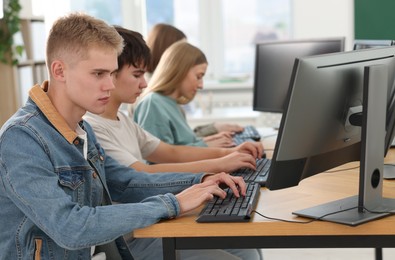 Photo of Students taking online exam indoors, selective focus