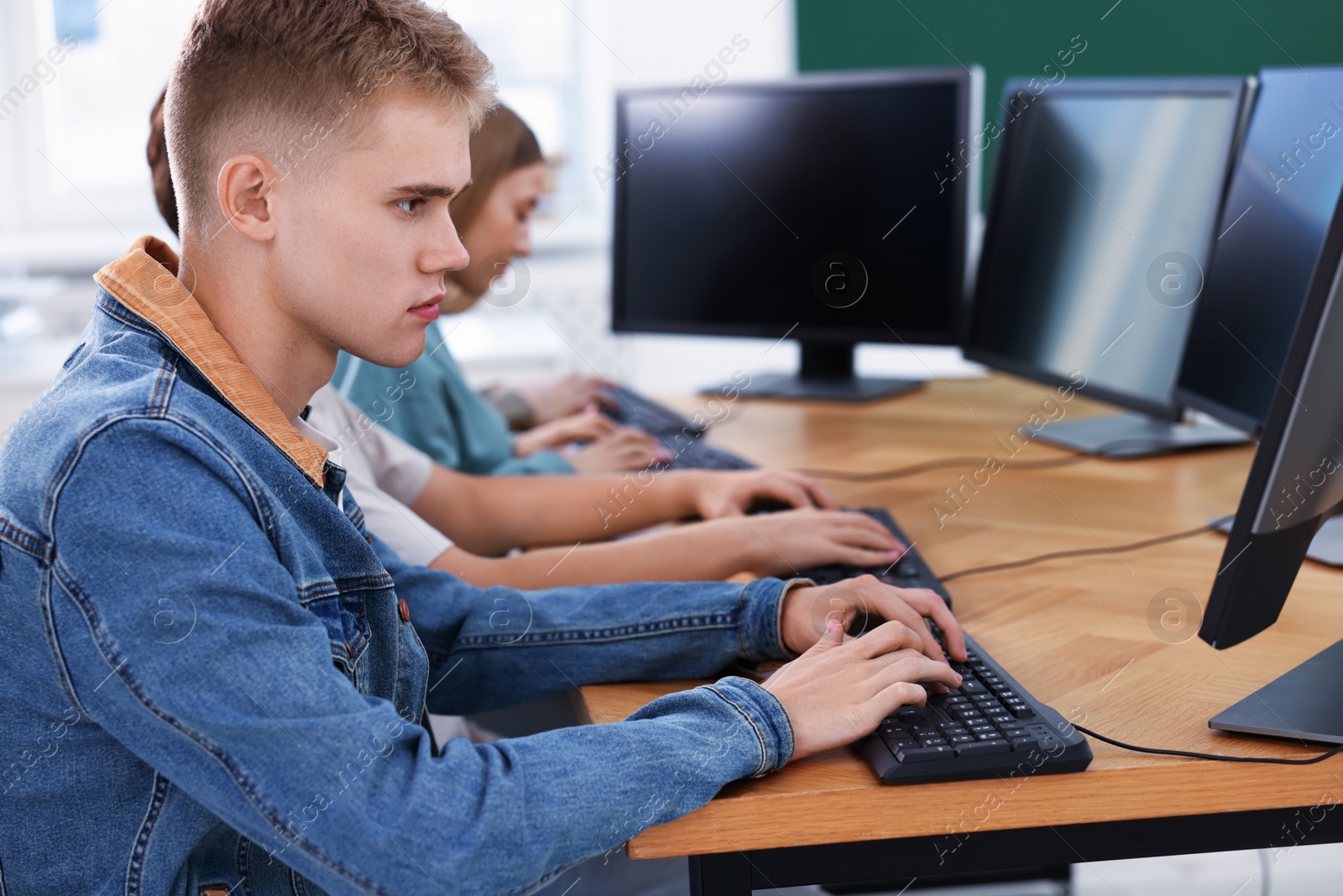 Photo of Students taking online exam indoors, selective focus