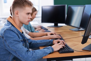Photo of Students taking online exam indoors, selective focus