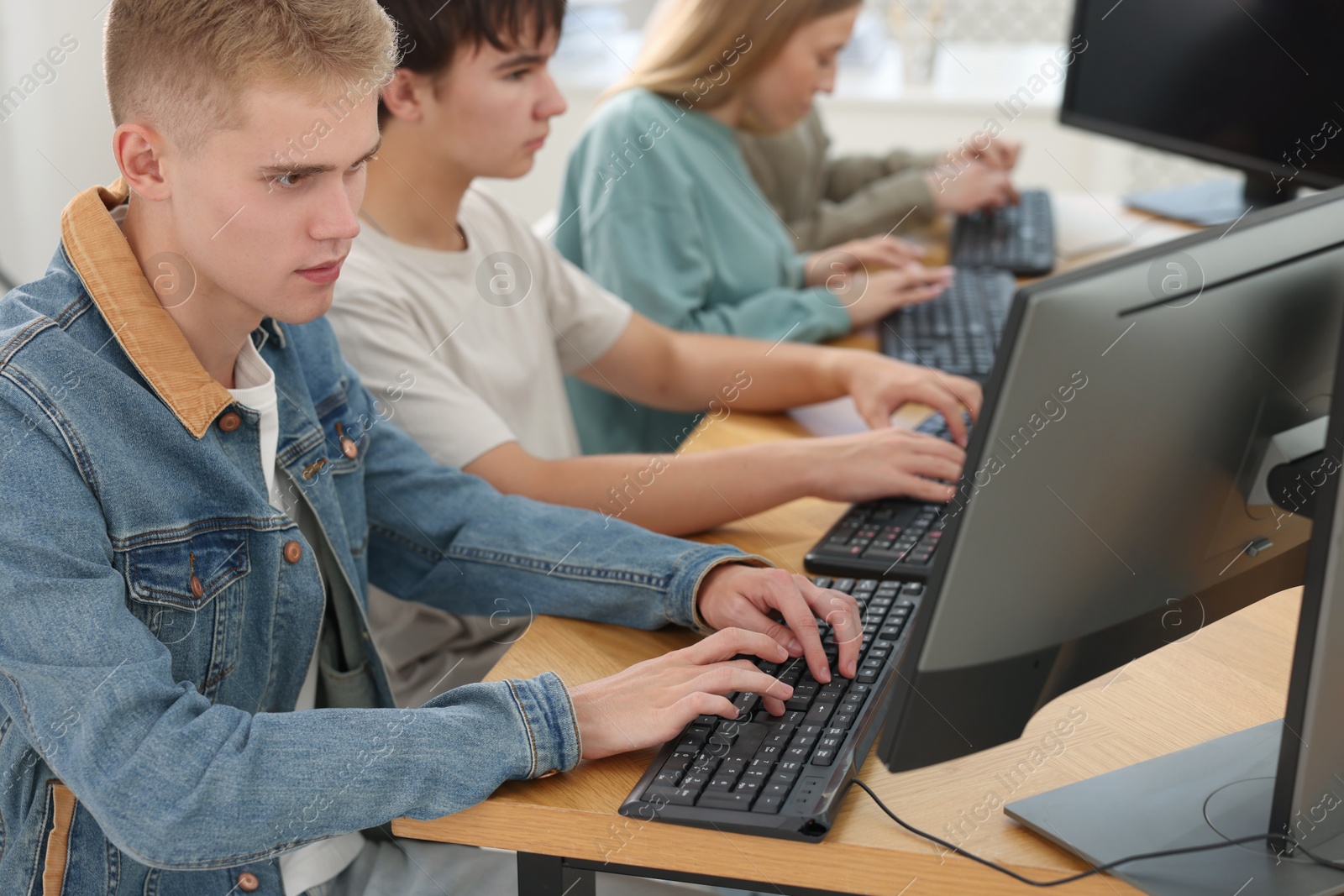 Photo of Students taking online exam indoors, selective focus