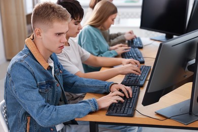 Photo of Students taking online exam indoors, selective focus