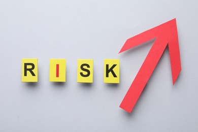 Photo of Word Risk and red arrow on light grey background, flat lay