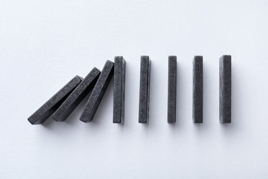 Photo of Risk. Domino tales falling on white background, flat lay