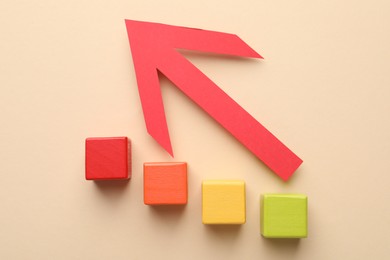Photo of Risk. Red arrow and colorful cubes on beige background, flat lay