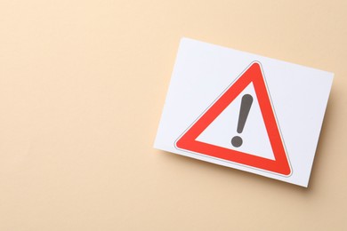 Photo of Risk. Sheet of paper with warning sign on beige background, top view. Space for text