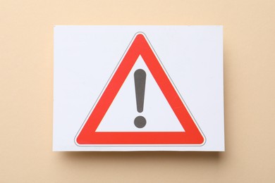 Photo of Risk. Sheet of paper with warning sign on beige background, top view
