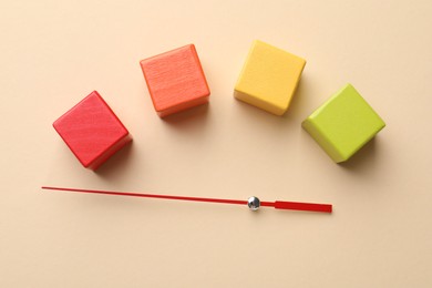 Photo of Risk. Red arrow and colorful cubes on beige background, flat lay