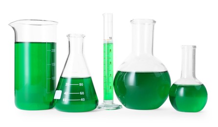 Photo of Different laboratory glassware with green liquid isolated on white