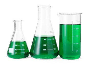 Photo of Different laboratory glassware with green liquid isolated on white