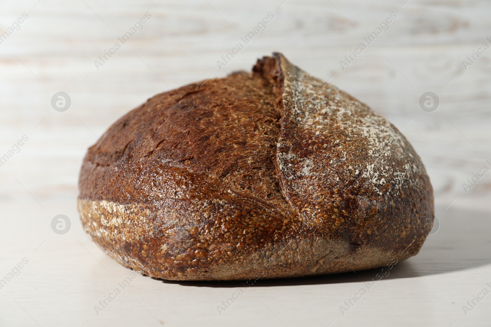 Photo of Loaf of fresh bread on white wooden table, closeup