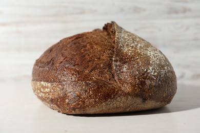 Photo of Loaf of fresh bread on white wooden table, closeup