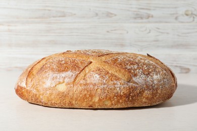 Photo of Loaf of fresh bread on white wooden table, closeup