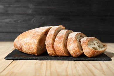 Photo of Fresh cut bread on light wooden table, closeup