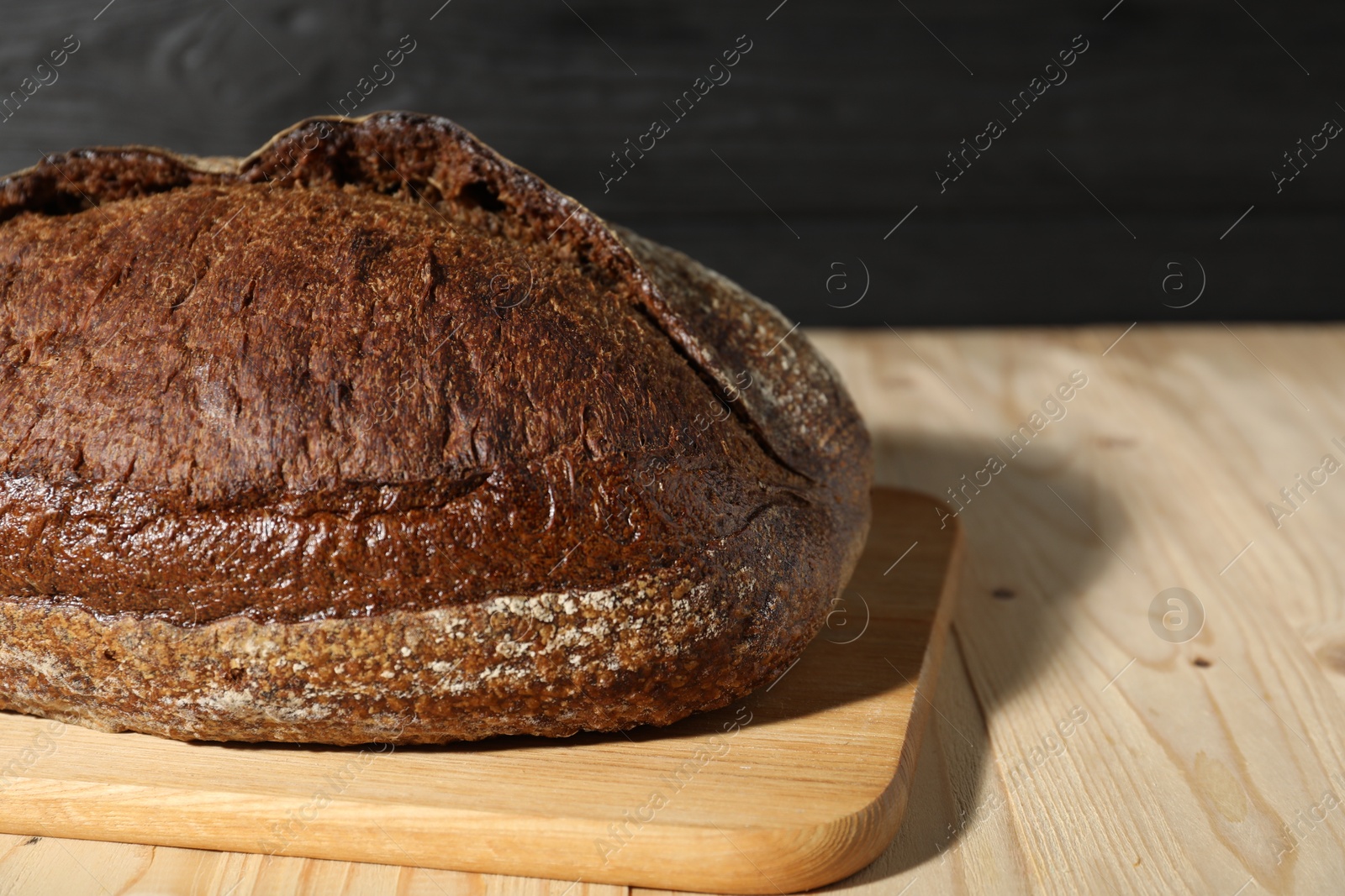 Photo of Loaf of fresh bread on light wooden table, closeup. Space for text