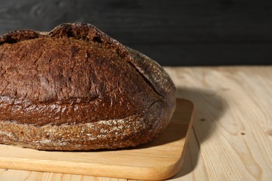 Photo of Loaf of fresh bread on light wooden table, closeup. Space for text