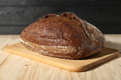 Photo of Loaf of fresh bread on light wooden table, closeup
