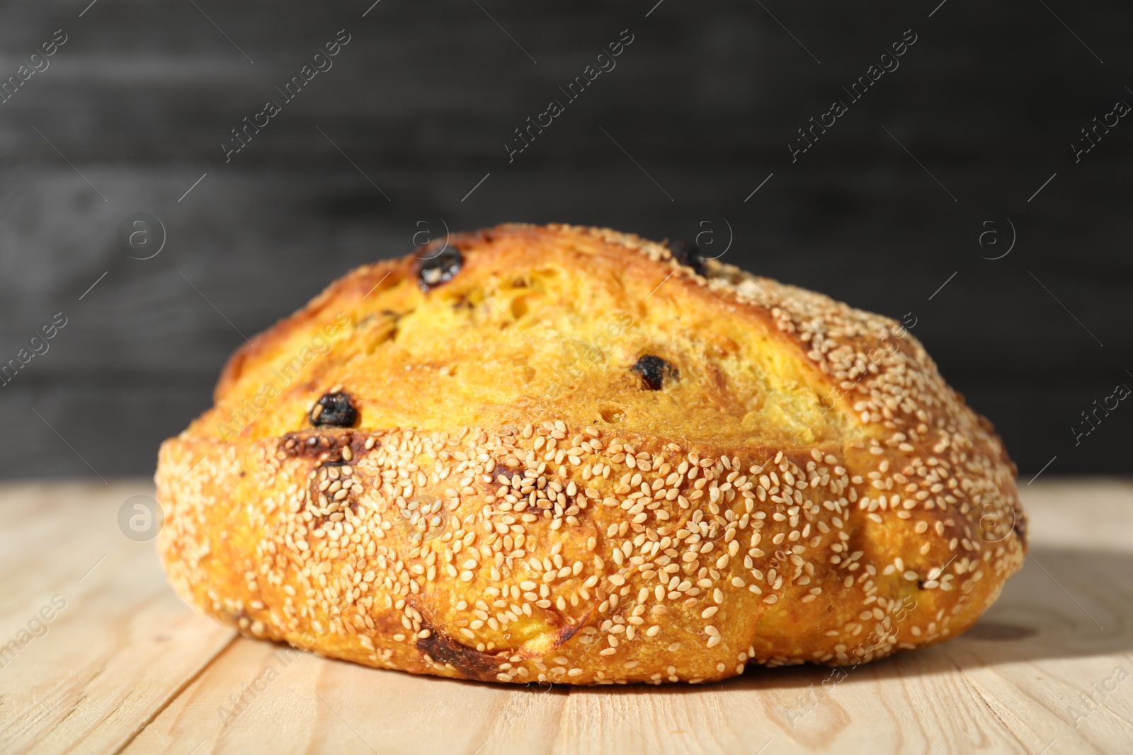 Loaf of fresh bread with sesame seeds and raisins on light wooden table, closeup Photo of Loaf of fresh bread with sesame seeds and raisins on light wooden table, closeup