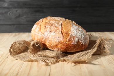 Photo of Loaf of fresh bread on light wooden table, closeup