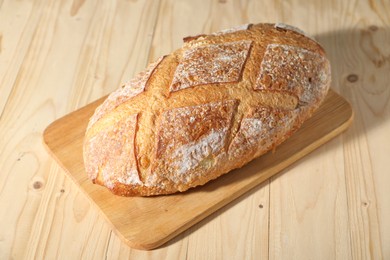 Photo of Loaf of fresh bread on light wooden table, closeup