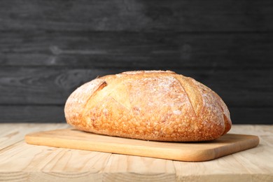 Photo of Loaf of fresh bread on light wooden table, closeup