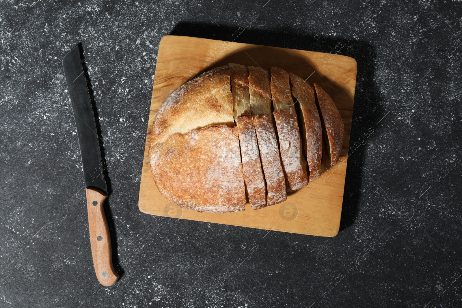 Fresh cut bread and knife on grey textured table, top view Photo of Fresh cut bread and knife on grey textured table, top view