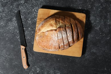 Photo of Fresh cut bread and knife on grey textured table, top view
