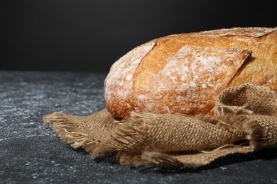 Photo of Loaf of fresh bread on grey textured table, closeup. Space for text